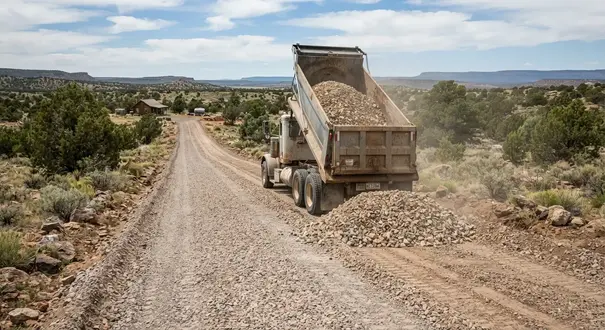 Dump truck delivering gravel onto a rural driveway in Apache County Arizona